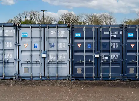 A side-by-side view of two shipping containers - one faded and dull, the other restored to a vibrant, deep blue -highlighting the contrast before and after colour restoration.