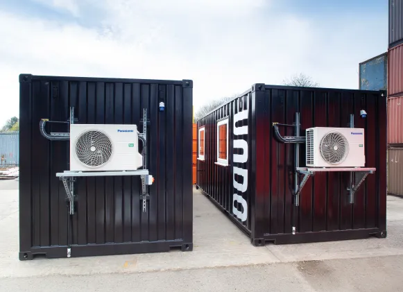 Two black container laboratories with prominent air conditioning units mounted on the front, custom-built for UNDO’s mobile research projects in remote environments.