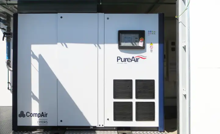 Close-up of a CompAir PureAir D110RS industrial compressor unit installed inside a containerised enclosure, featuring a control panel and ventilation grilles for efficient air system operation.